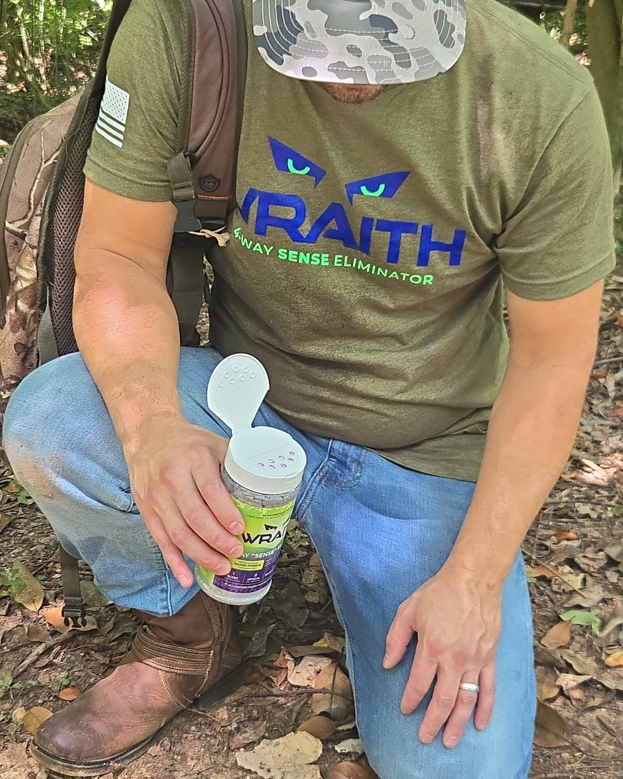 In the field: a hunter kneeling in the woods holding the WRAITH 16 oz shaker with its scoop