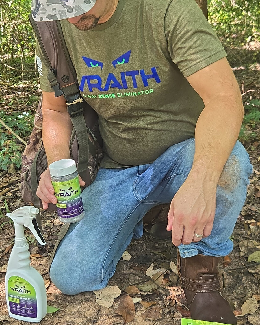 In the field: a hunter kneeling with the WRAITH 16 oz shaker, spray bottle on the ground beside him