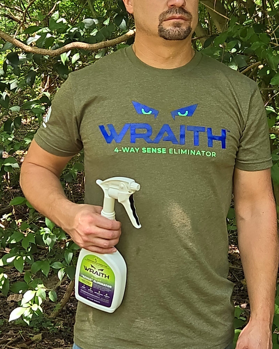 In the field: a hunter standing in green timber holding the WRAITH 23 oz spray bottle