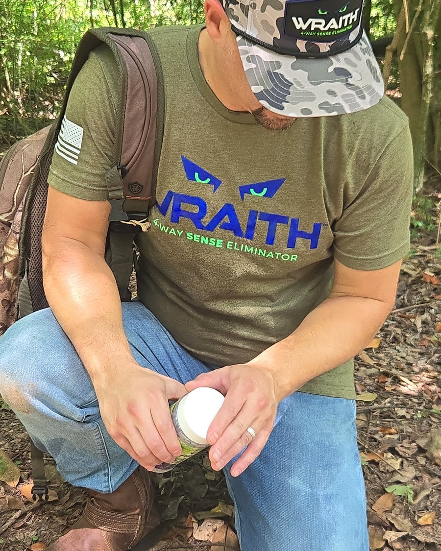 In the field: a hunter kneeling in the woods opening the WRAITH 32 oz bulk canister