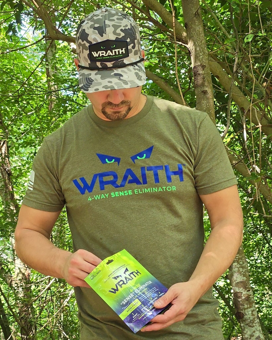 In the field: a hunter reading the label on the WRAITH 4 oz refill pouch in green timber