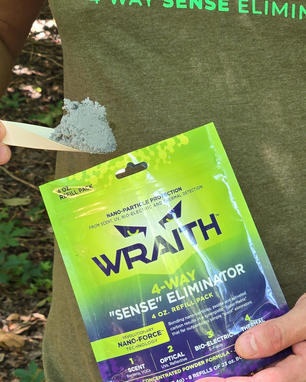 A scoop of gray Wraith powder concentrate held above the 4 oz refill pack