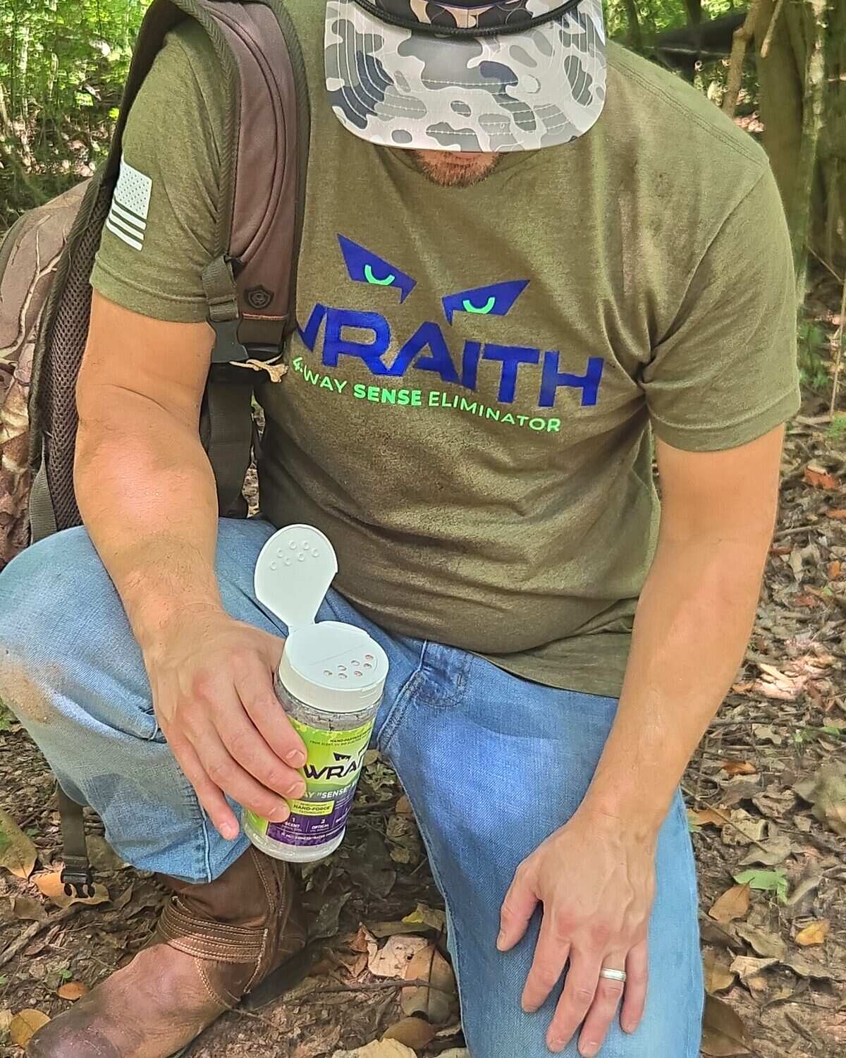 A hunter kneeling on the forest floor, measuring WRAITH powder from the 32 oz canister with the scoop